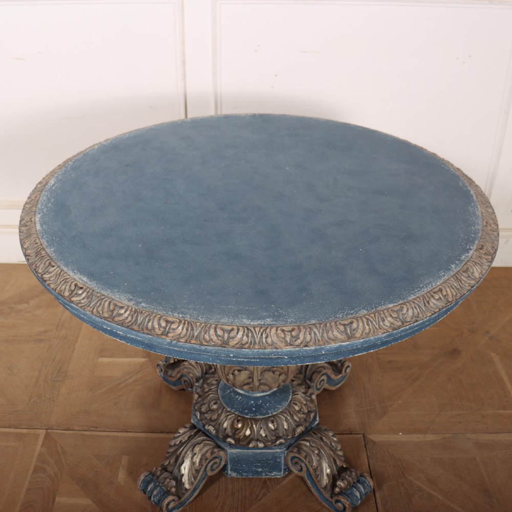A circular 1920s German centre table featuring a distressed slate blue painted finish, gilt carved acanthus leaf pedestal, and scroll feet. View IX