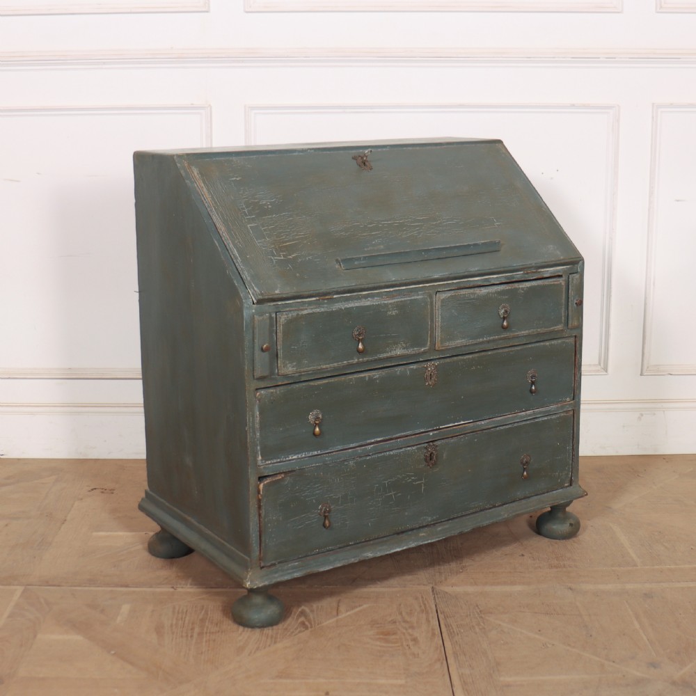 An 18th-century English slant-front bureau with a distressed grey-green painted finish, brass pull handles, and turned feet.