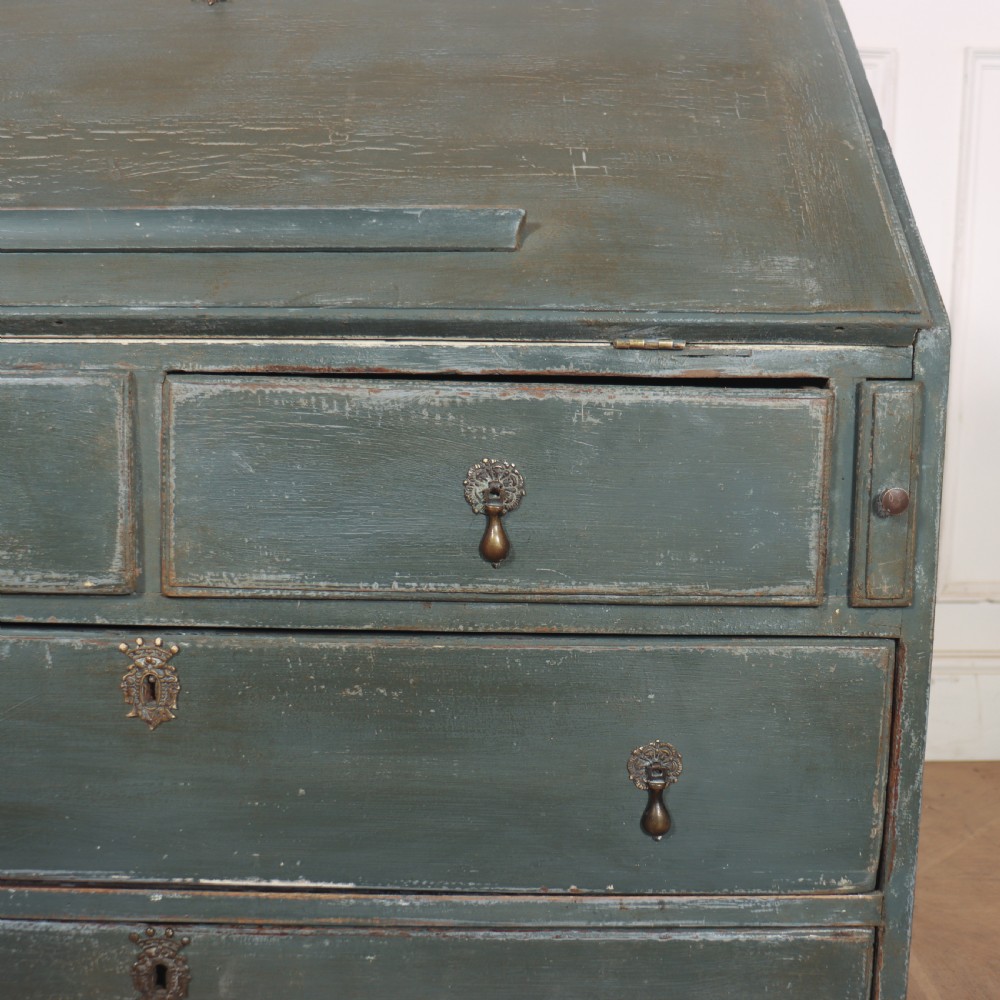 An 18th-century English slant-front bureau with a distressed grey-green painted finish, brass pull handles, and turned feet. View VII