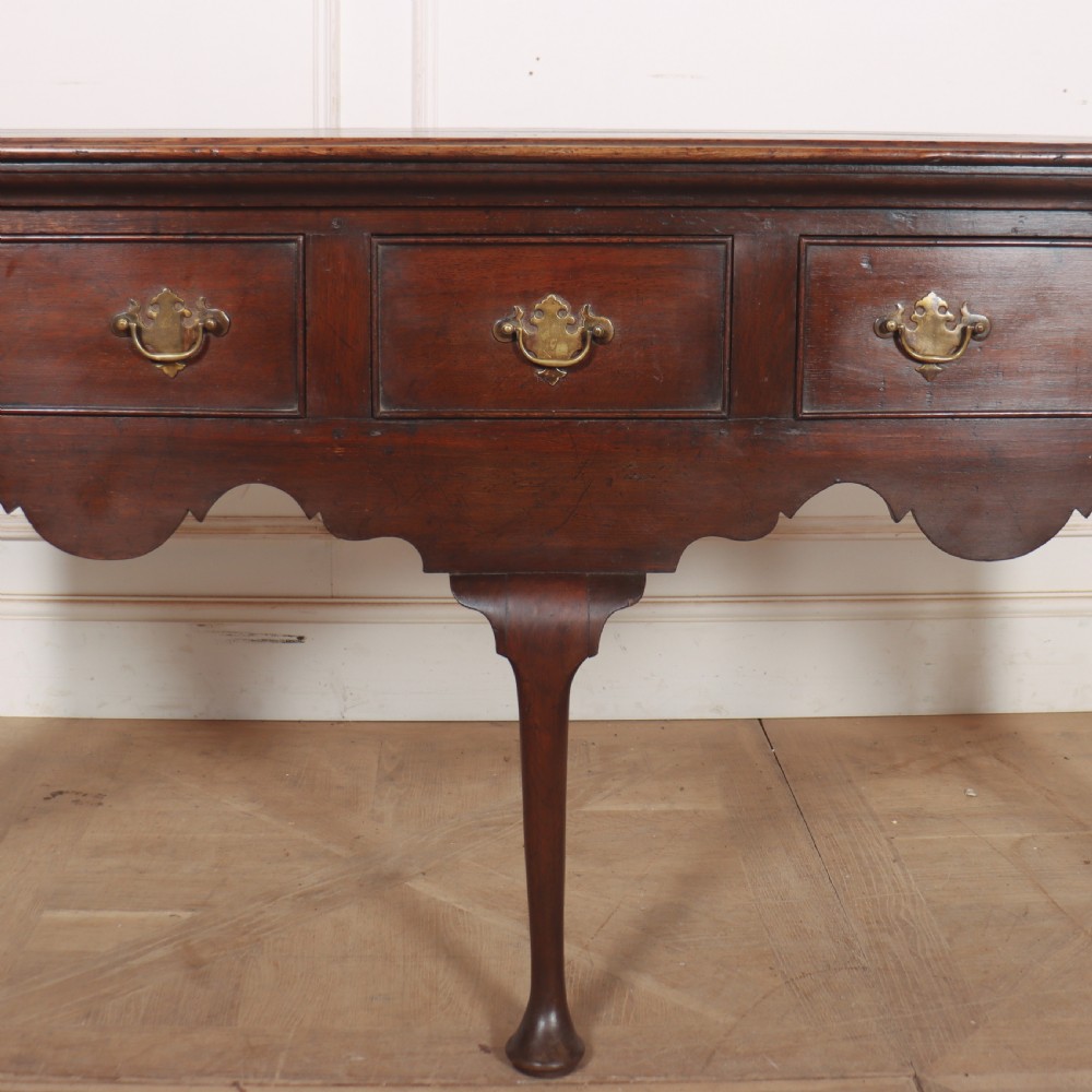 An 18th-century style dark oak dresser base featuring three frieze drawers, brass handles, a shaped apron, and elegant cabriole legs. View III
