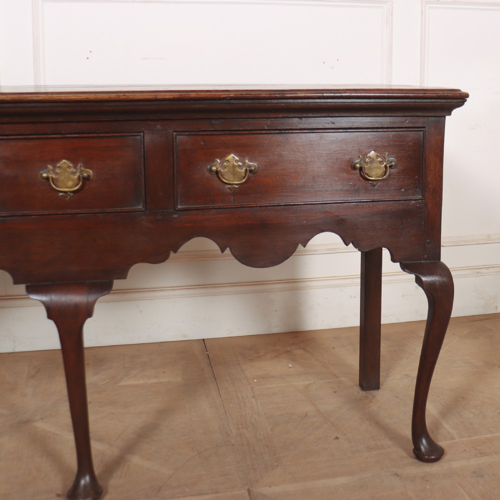 An 18th-century style dark oak dresser base featuring three frieze drawers, brass handles, a shaped apron, and elegant cabriole legs. View IV