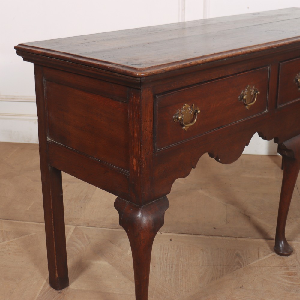 An 18th-century style dark oak dresser base featuring three frieze drawers, brass handles, a shaped apron, and elegant cabriole legs. View VII