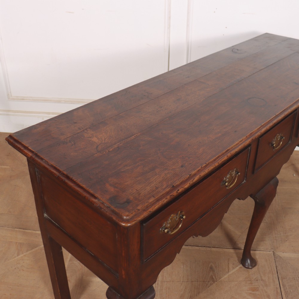 An 18th-century style dark oak dresser base featuring three frieze drawers, brass handles, a shaped apron, and elegant cabriole legs. View IX