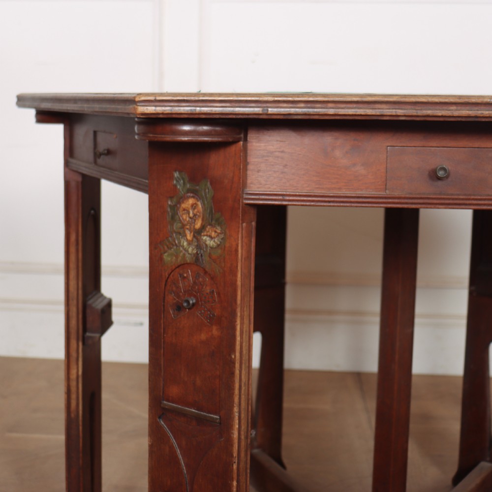 An antique hexagonal Arts and Crafts walnut card table featuring a green baize top, pierced leg details, and integrated drawers. View II