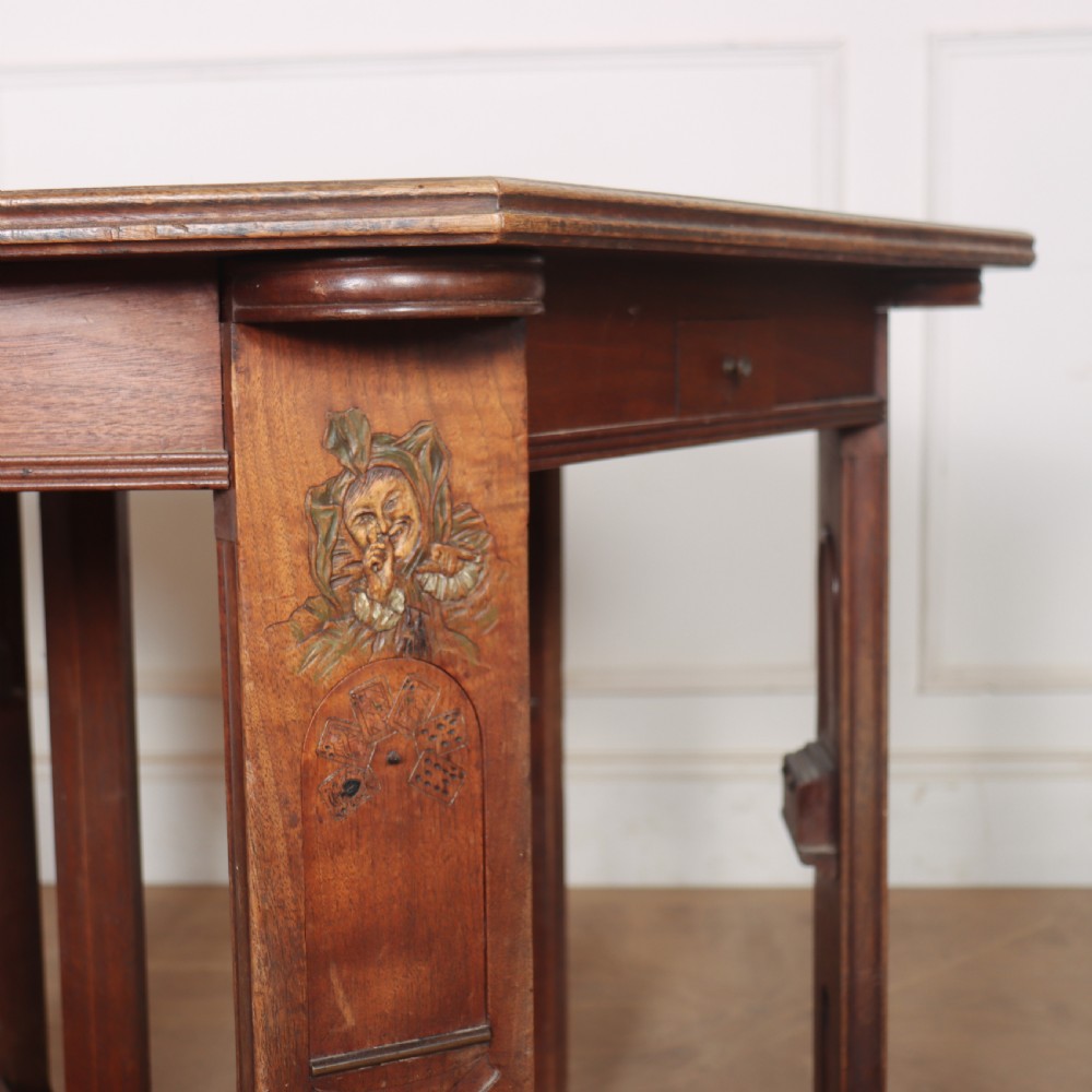 An antique hexagonal Arts and Crafts walnut card table featuring a green baize top, pierced leg details, and integrated drawers. View III