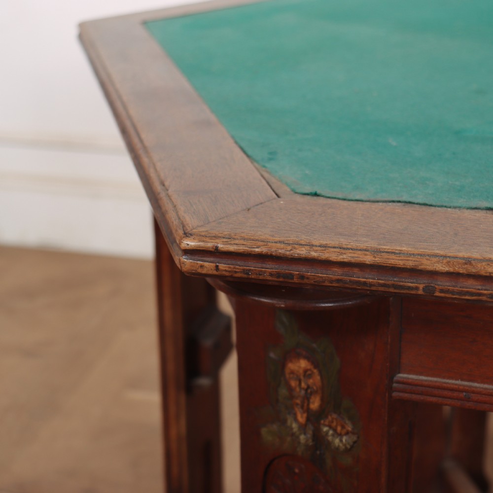 An antique hexagonal Arts and Crafts walnut card table featuring a green baize top, pierced leg details, and integrated drawers. View X