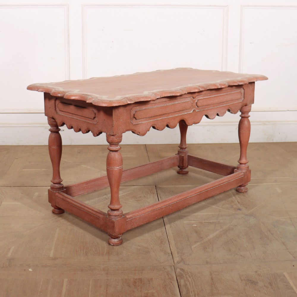 An 18th-century Dutch Baroque side table with a terracotta red painted finish, scalloped top, shaped apron, turned baluster legs, and a box stretcher.