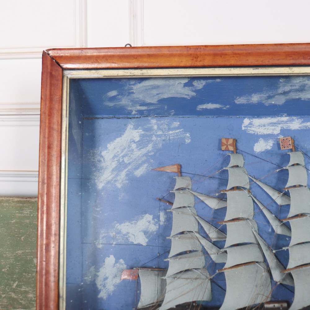 A framed glazed maritime diorama featuring a carved three-masted sailing vessel on a choppy painted sea set against a blue sky with a lighthouse. View II