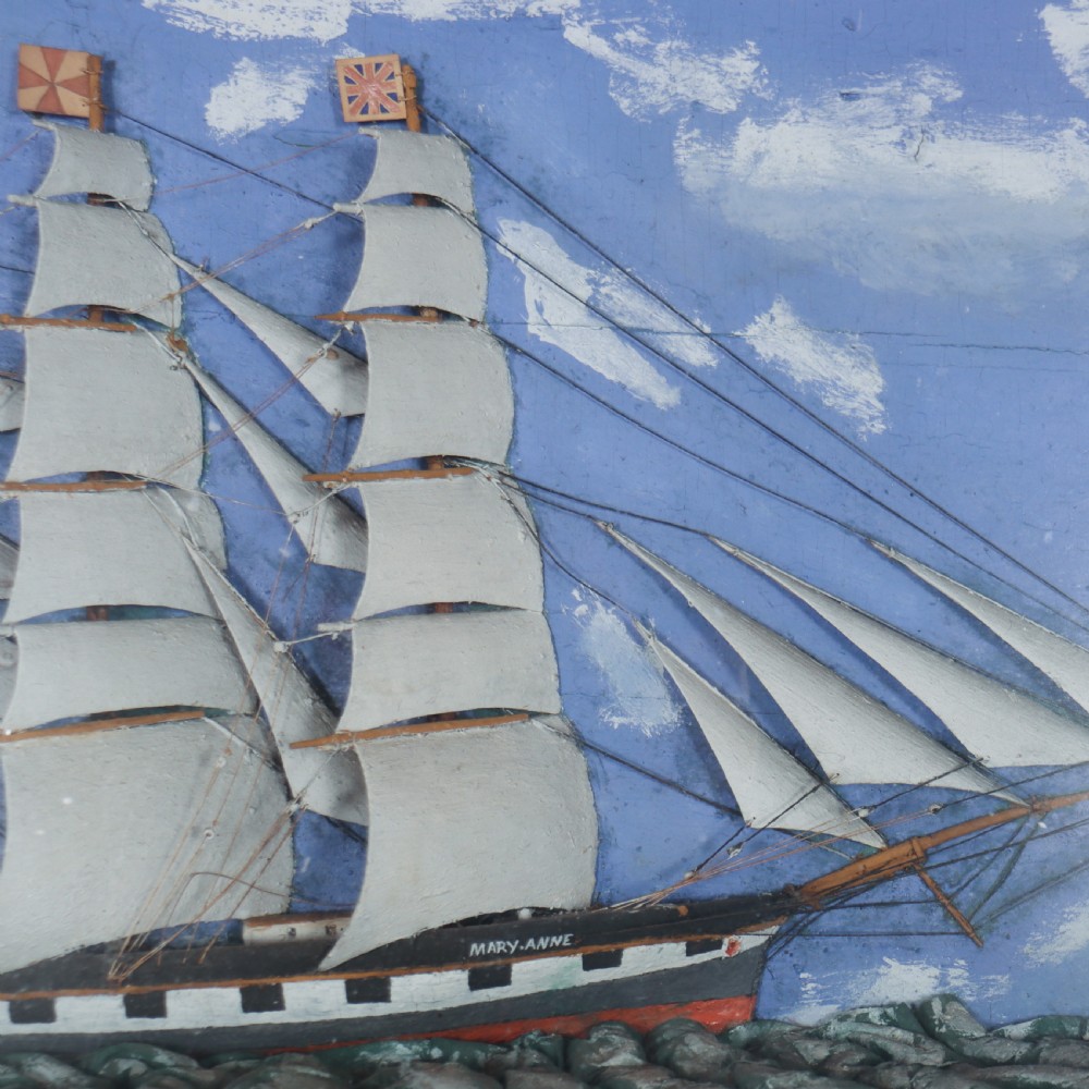 A framed glazed maritime diorama featuring a carved three-masted sailing vessel on a choppy painted sea set against a blue sky with a lighthouse. View III