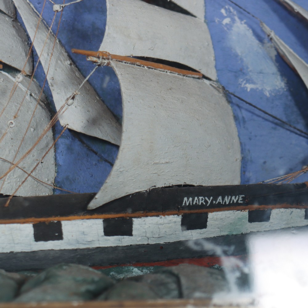 A framed glazed maritime diorama featuring a carved three-masted sailing vessel on a choppy painted sea set against a blue sky with a lighthouse. View VII