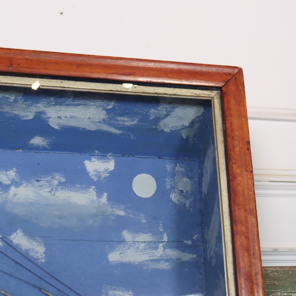 A framed glazed maritime diorama featuring a carved three-masted sailing vessel on a choppy painted sea set against a blue sky with a lighthouse. View VIII
