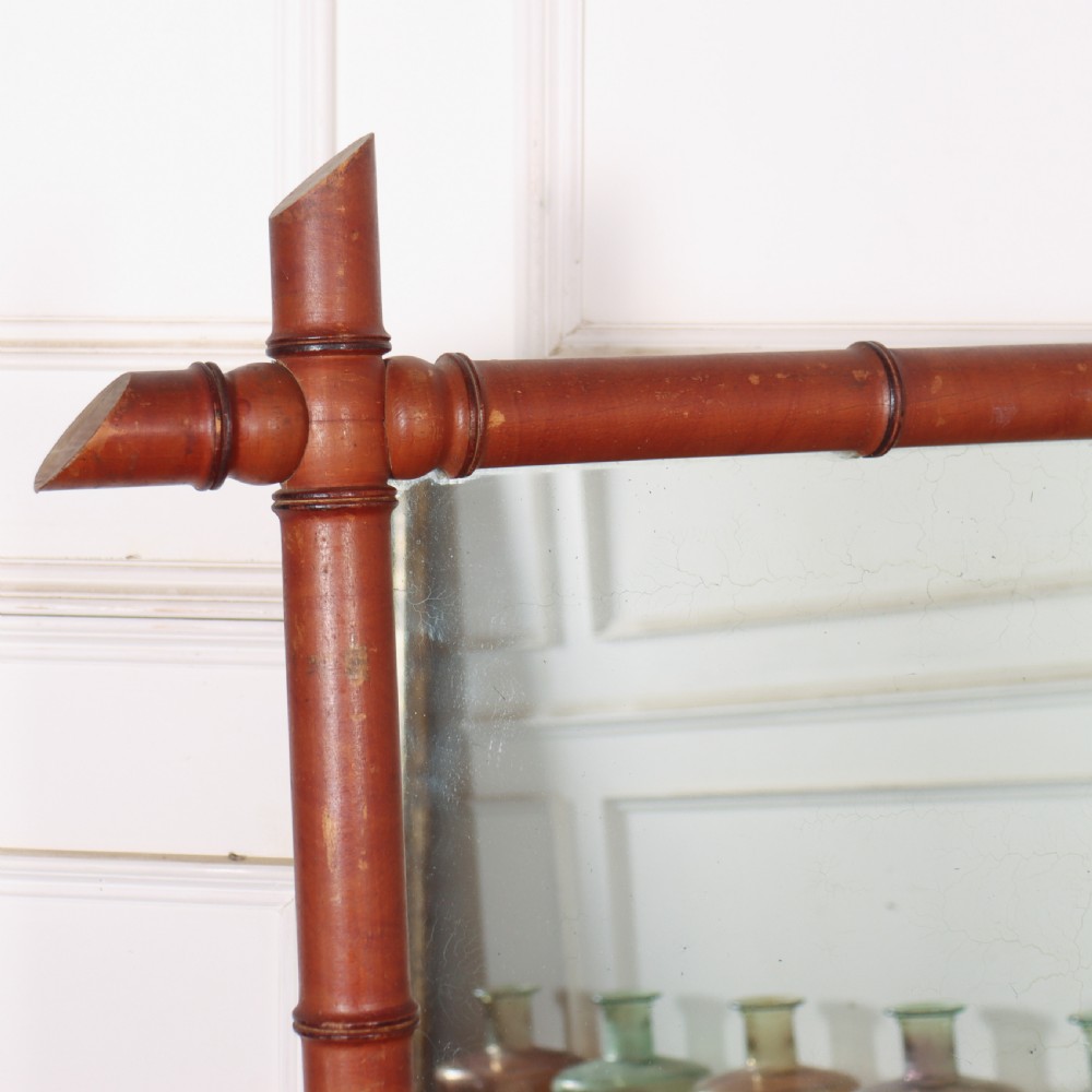 A large rectangular mirror framed in warm brown turned wood designed to mimic bamboo with extending corner joints. View II