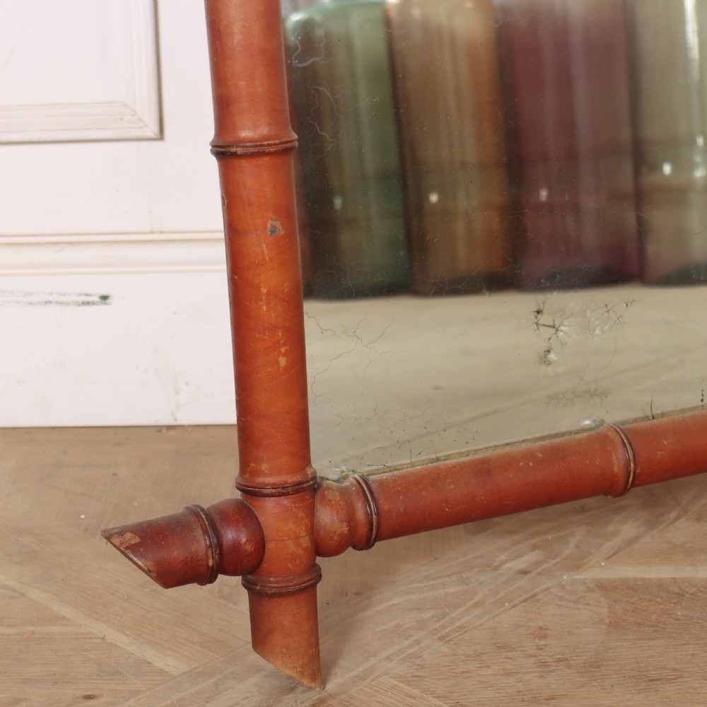 A large rectangular mirror framed in warm brown turned wood designed to mimic bamboo with extending corner joints. View V