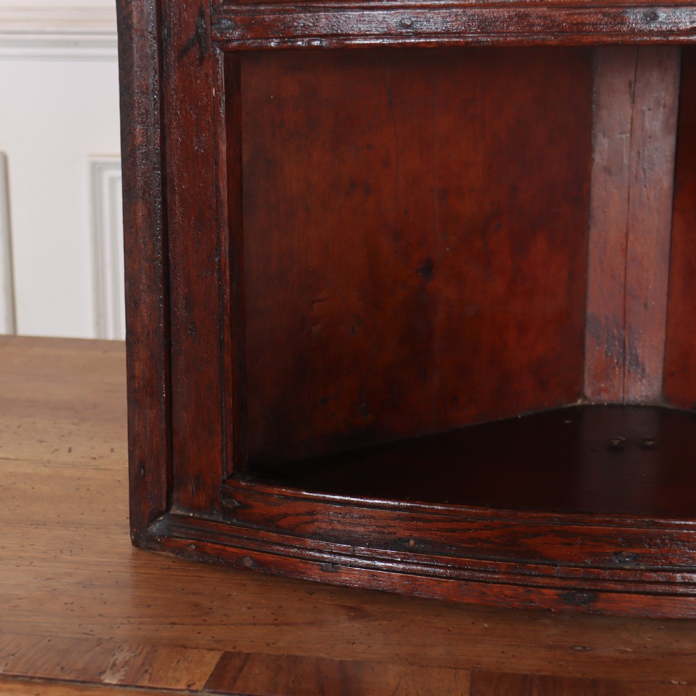 An 18th-century English dark wood hanging corner cupboard with three open curved shelves and moulded cornice. View IV