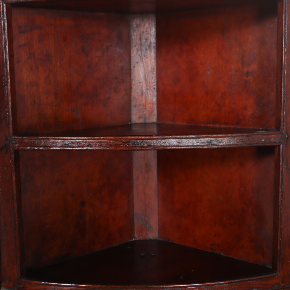 An 18th-century English dark wood hanging corner cupboard with three open curved shelves and moulded cornice. View VI