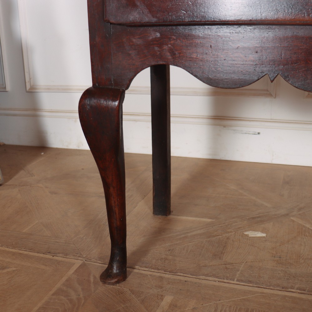 An 18th-century English oak dresser base featuring three drawers with brass handles, a scalloped apron, and cabriole legs. View IV