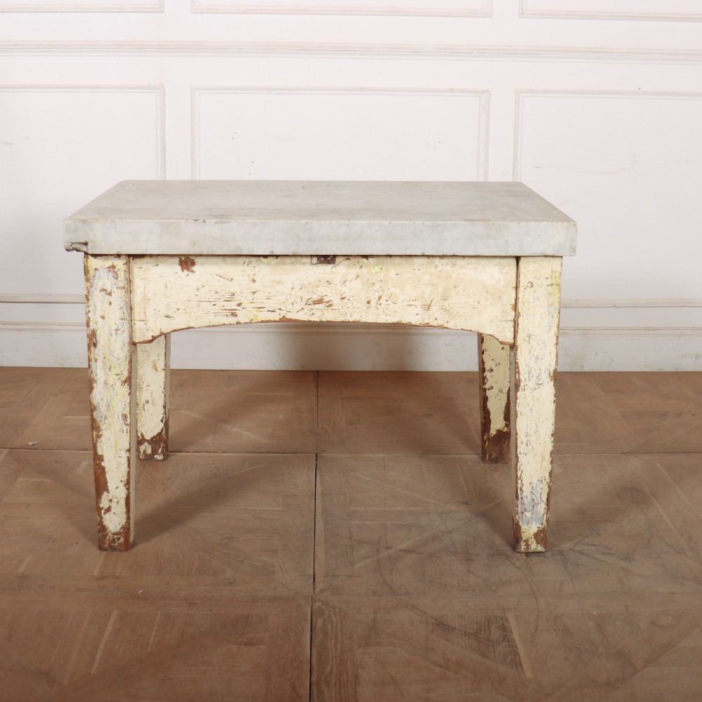An antique pastry table featuring a distressed cream painted wooden frame, a single central drawer with a brass handle, and a thick grey metal top. View XI