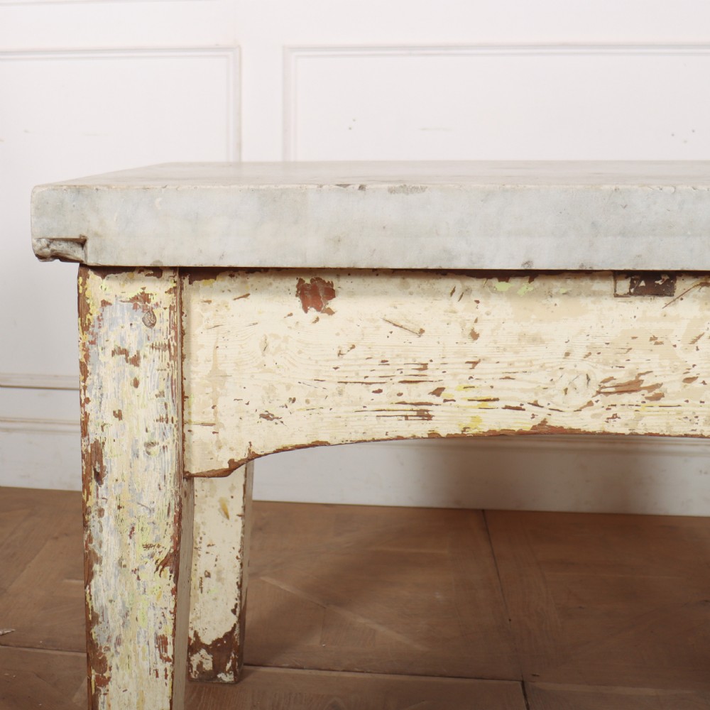 An antique pastry table featuring a distressed cream painted wooden frame, a single central drawer with a brass handle, and a thick grey metal top. View XII
