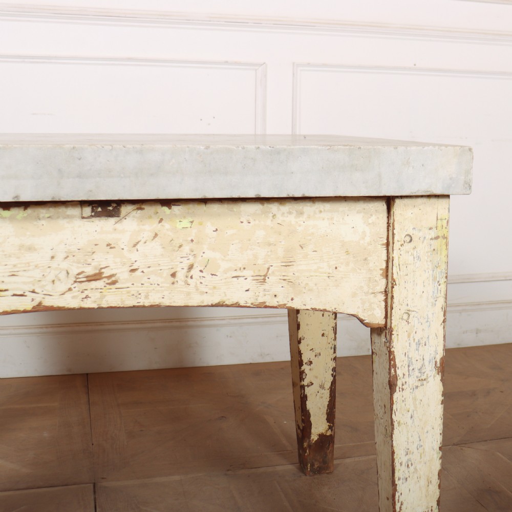 An antique pastry table featuring a distressed cream painted wooden frame, a single central drawer with a brass handle, and a thick grey metal top. View XIII