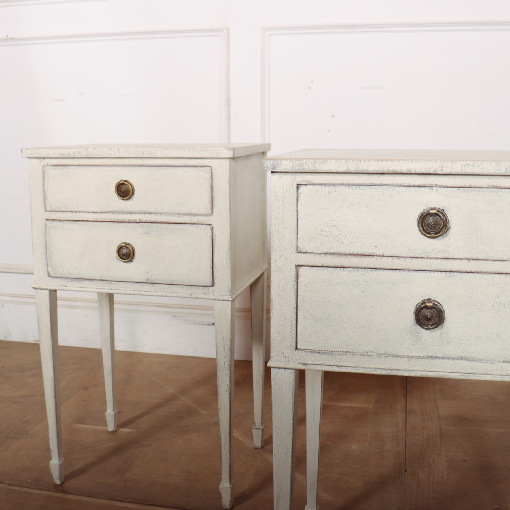 A pair of off-white painted Swedish Gustavian style bedside tables, each featuring two drawers with brass ring pull handles and slender tapered legs. View III