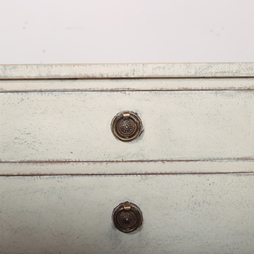 A pair of off-white painted Swedish Gustavian style bedside tables, each featuring two drawers with brass ring pull handles and slender tapered legs. View V