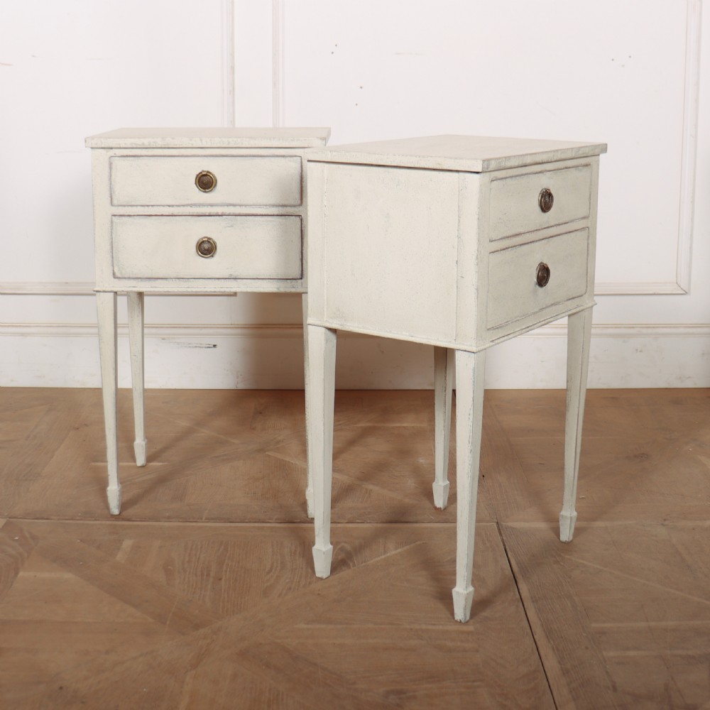 A pair of off-white painted Swedish Gustavian style bedside tables, each featuring two drawers with brass ring pull handles and slender tapered legs. View VI