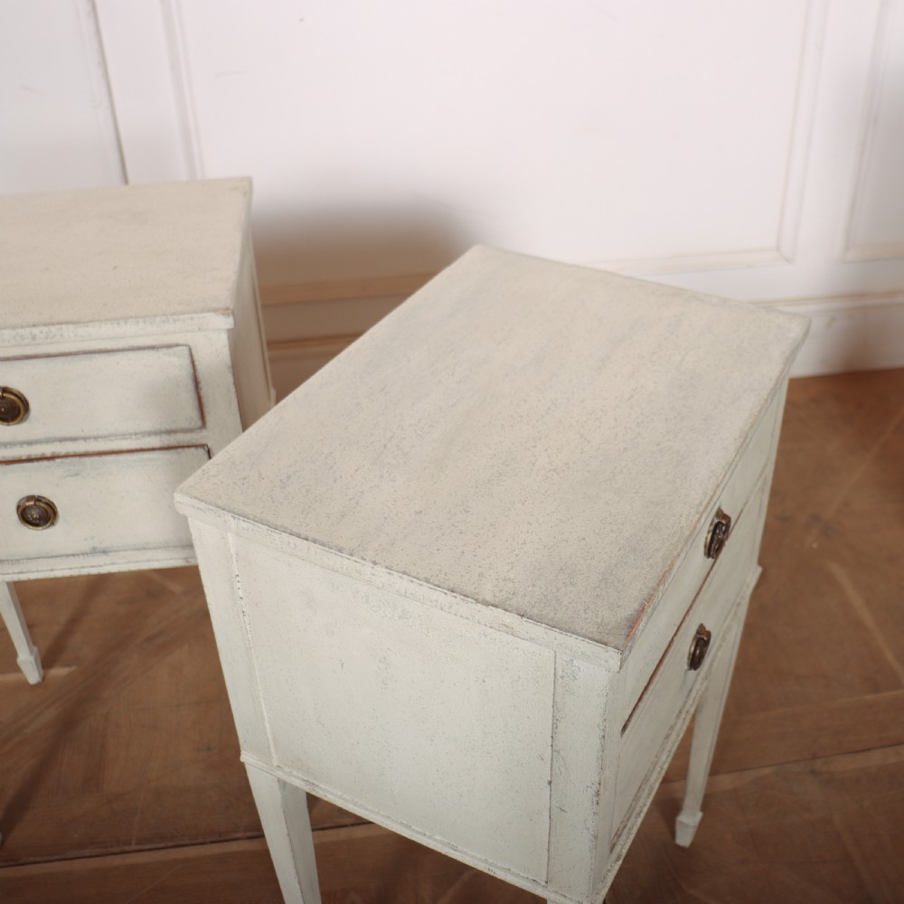 A pair of off-white painted Swedish Gustavian style bedside tables, each featuring two drawers with brass ring pull handles and slender tapered legs. View VII