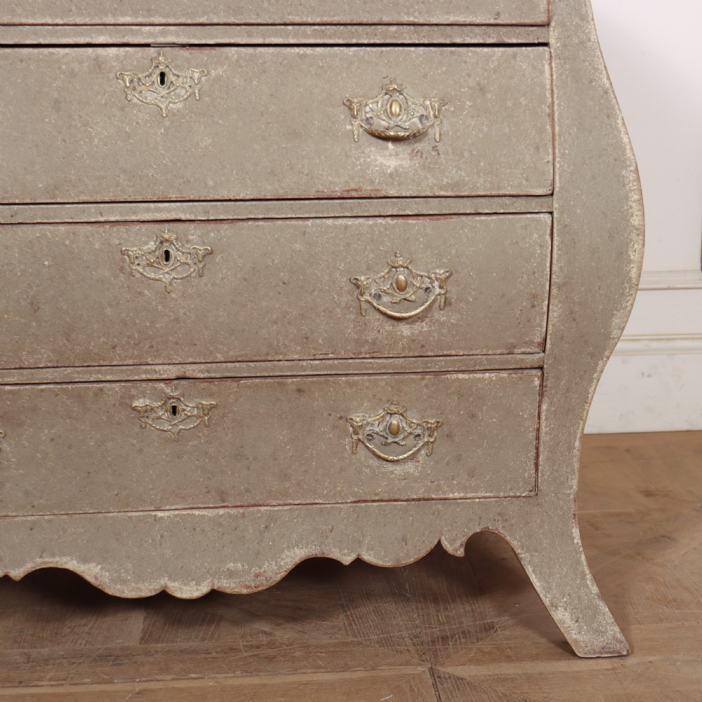 A 19th-century Dutch bombe commode featuring a distressed grey painted finish, four drawers, and decorative brass hardware. View V