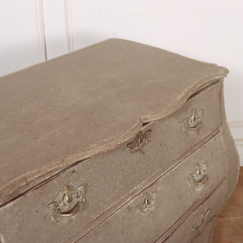 A 19th-century Dutch bombe commode featuring a distressed grey painted finish, four drawers, and decorative brass hardware. View X