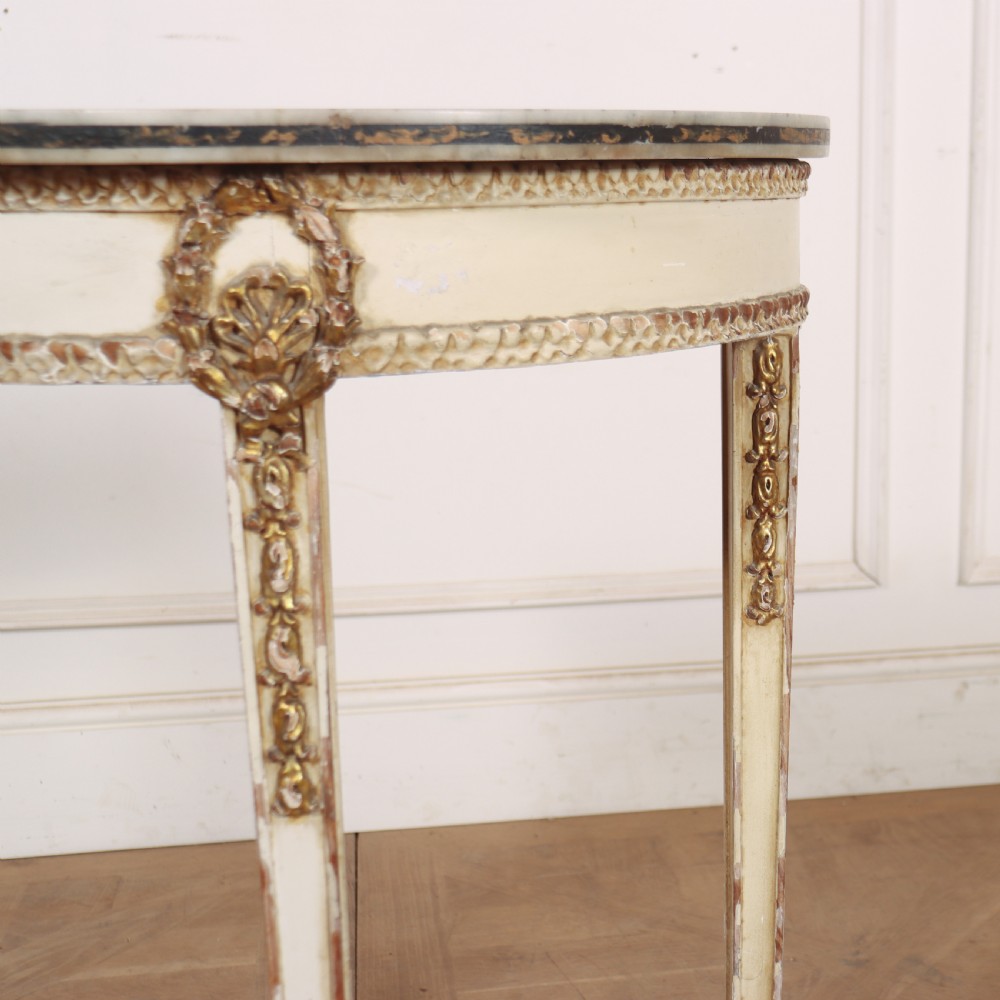 A French Louis XVI style cream painted and gilded demi-lune console table with tapered legs. View IV