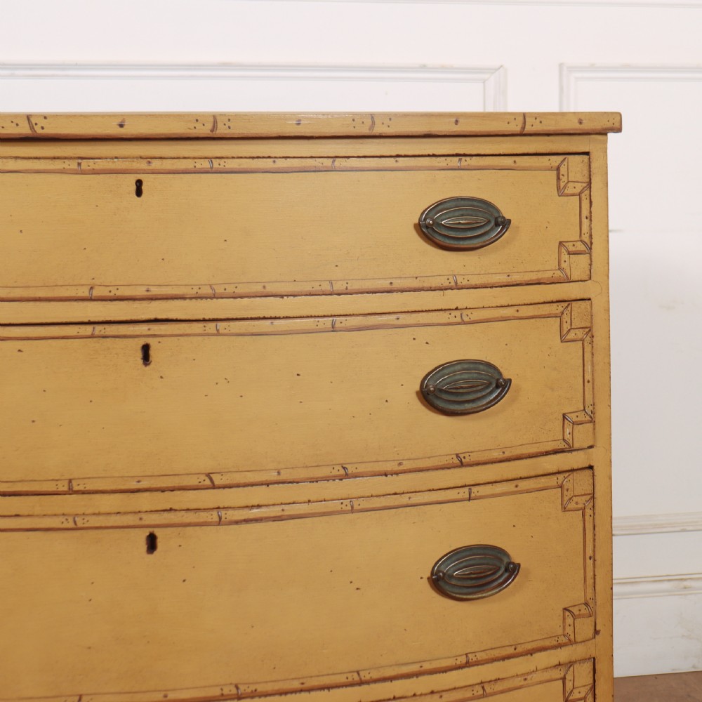A Georgian bowfront chest of drawers with four graduated drawers painted in yellow with line borders and oval brass drop handles. View III