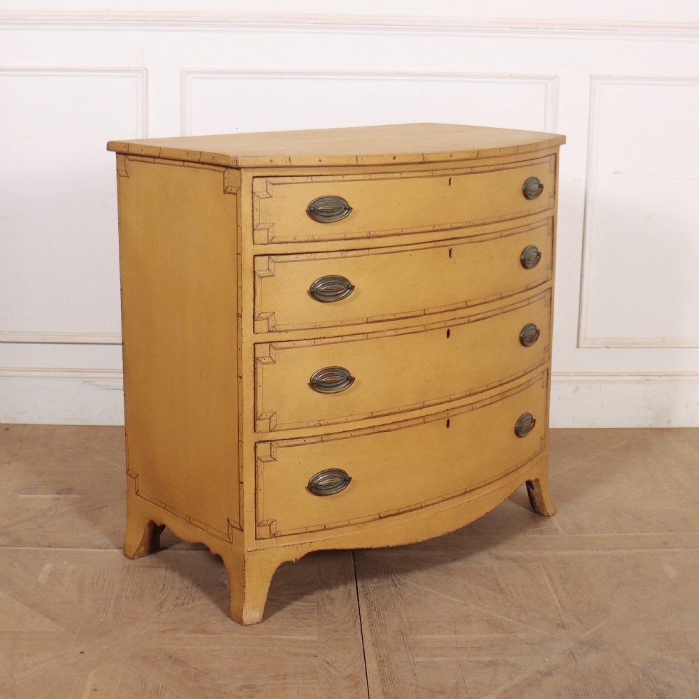 A Georgian bowfront chest of drawers with four graduated drawers painted in yellow with line borders and oval brass drop handles. View VII