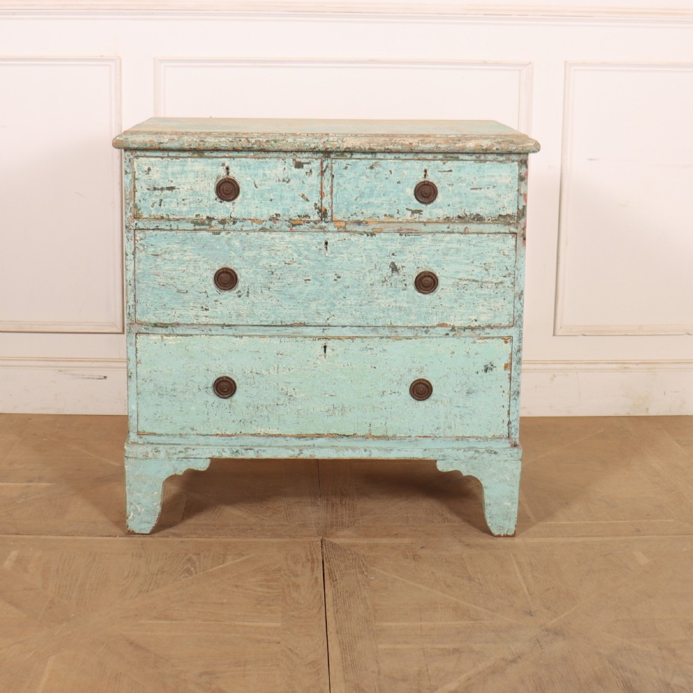 An English chest of drawers with distressed pale blue original paint, featuring two short drawers over two long drawers and turned dark wooden handles.
