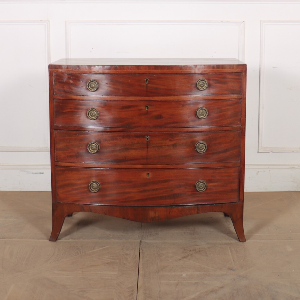 An antique mahogany bowfront chest of drawers featuring four graduated drawers with circular brass handles and splay bracket feet.