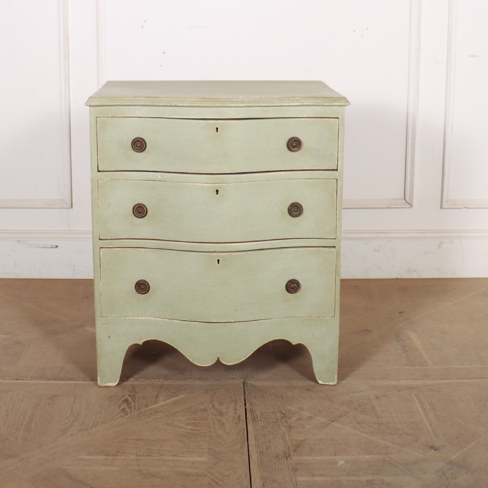 A Swedish serpentine painted commode featuring three drawers with brass pulls and a shaped apron in a muted green finish.