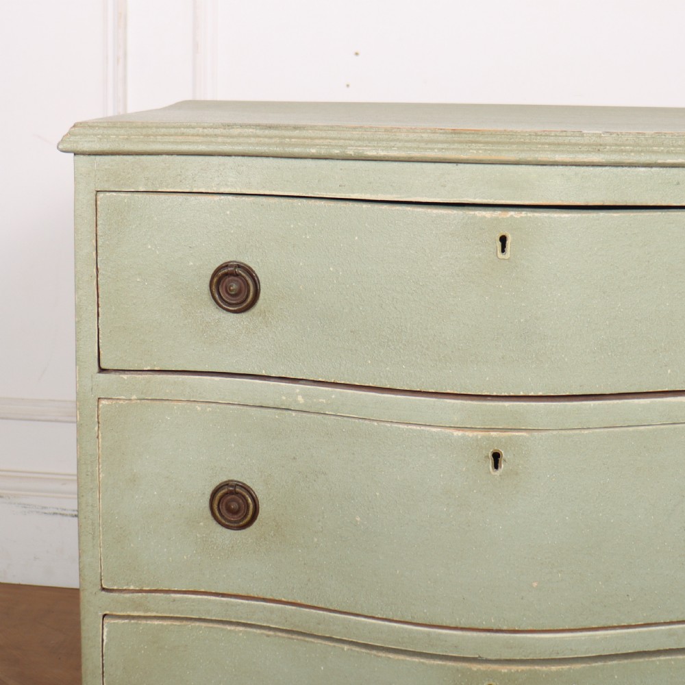 A Swedish serpentine painted commode featuring three drawers with brass pulls and a shaped apron in a muted green finish. View II