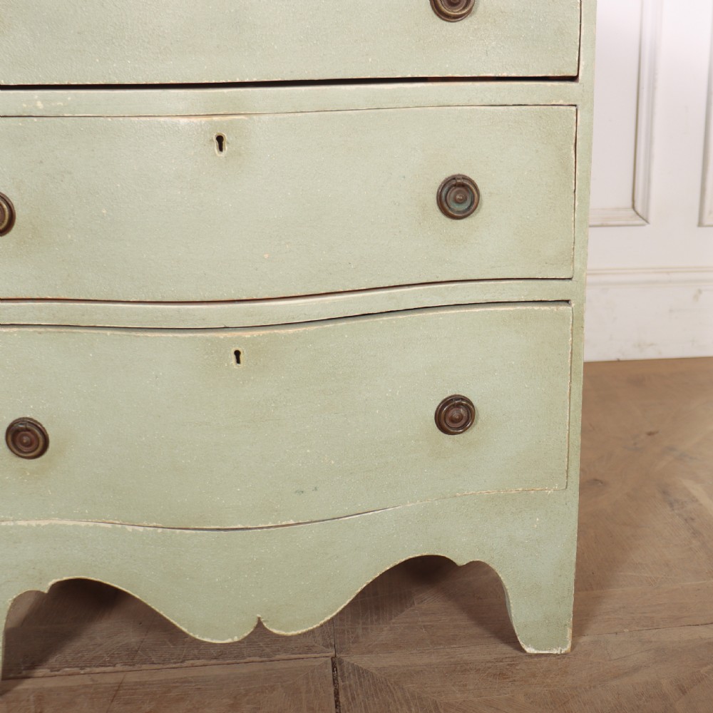 A Swedish serpentine painted commode featuring three drawers with brass pulls and a shaped apron in a muted green finish. View IV