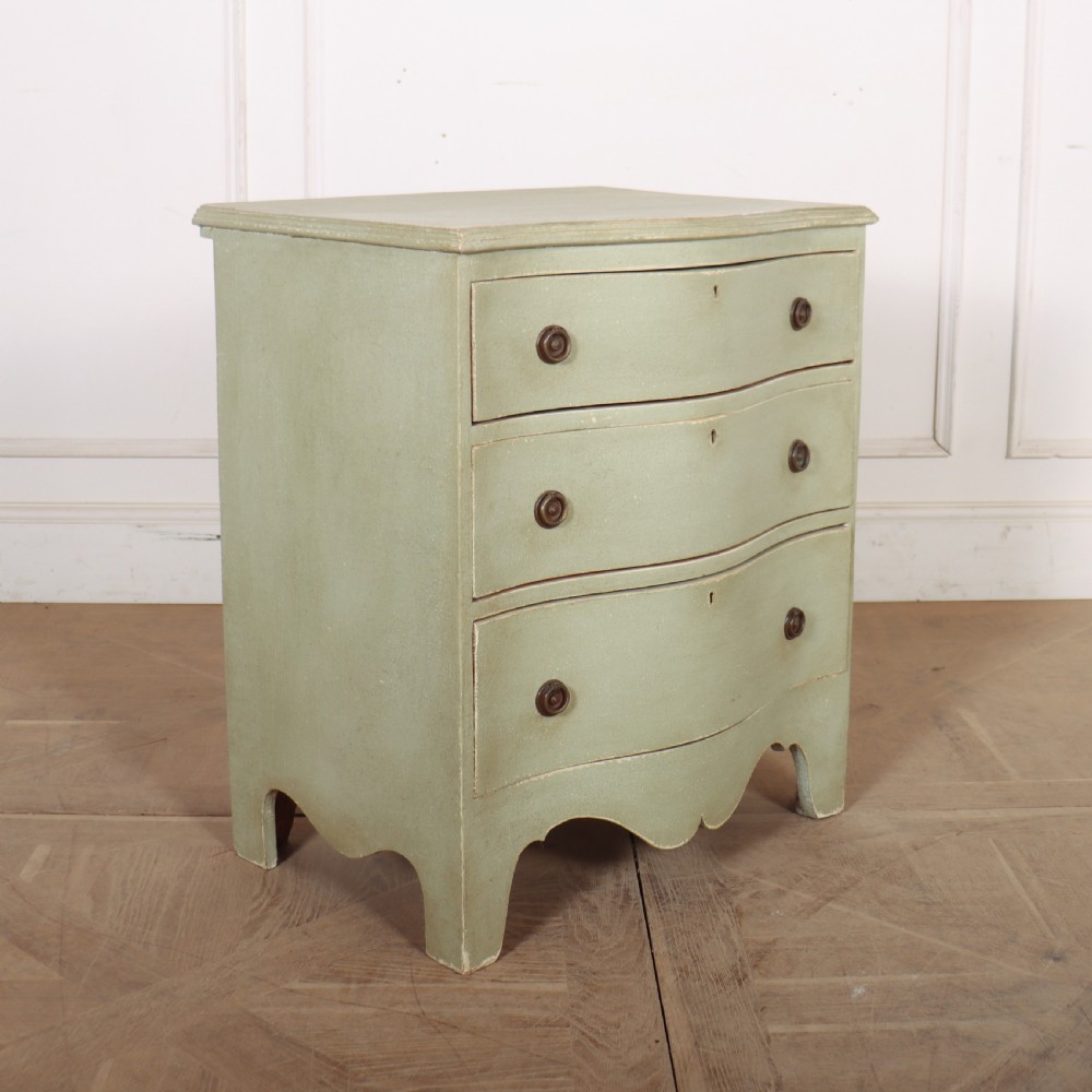 A Swedish serpentine painted commode featuring three drawers with brass pulls and a shaped apron in a muted green finish. View VI