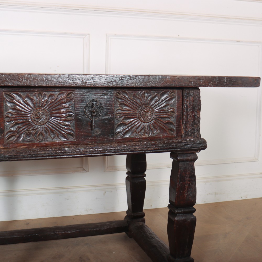 A 17th-century Spanish dark oak console table featuring carved drawer fronts with rosette motifs, turned legs, iron handles, and a box stretcher base. View IV