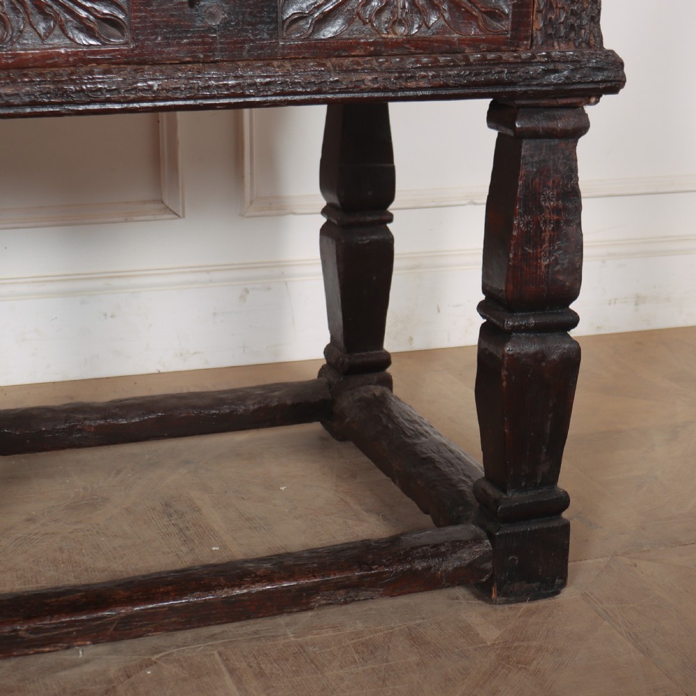 A 17th-century Spanish dark oak console table featuring carved drawer fronts with rosette motifs, turned legs, iron handles, and a box stretcher base. View VII
