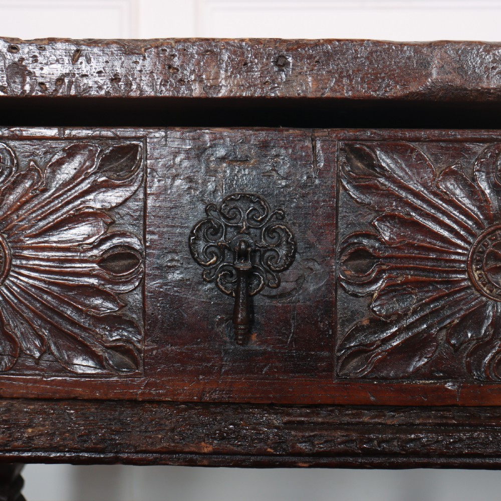 A 17th-century Spanish dark oak console table featuring carved drawer fronts with rosette motifs, turned legs, iron handles, and a box stretcher base. View IX