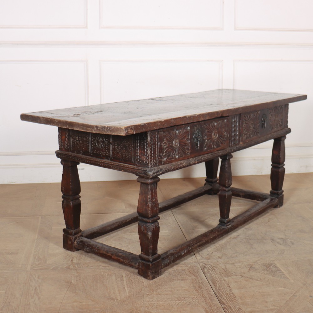 A 17th-century Spanish dark oak console table featuring carved drawer fronts with rosette motifs, turned legs, iron handles, and a box stretcher base. View XI
