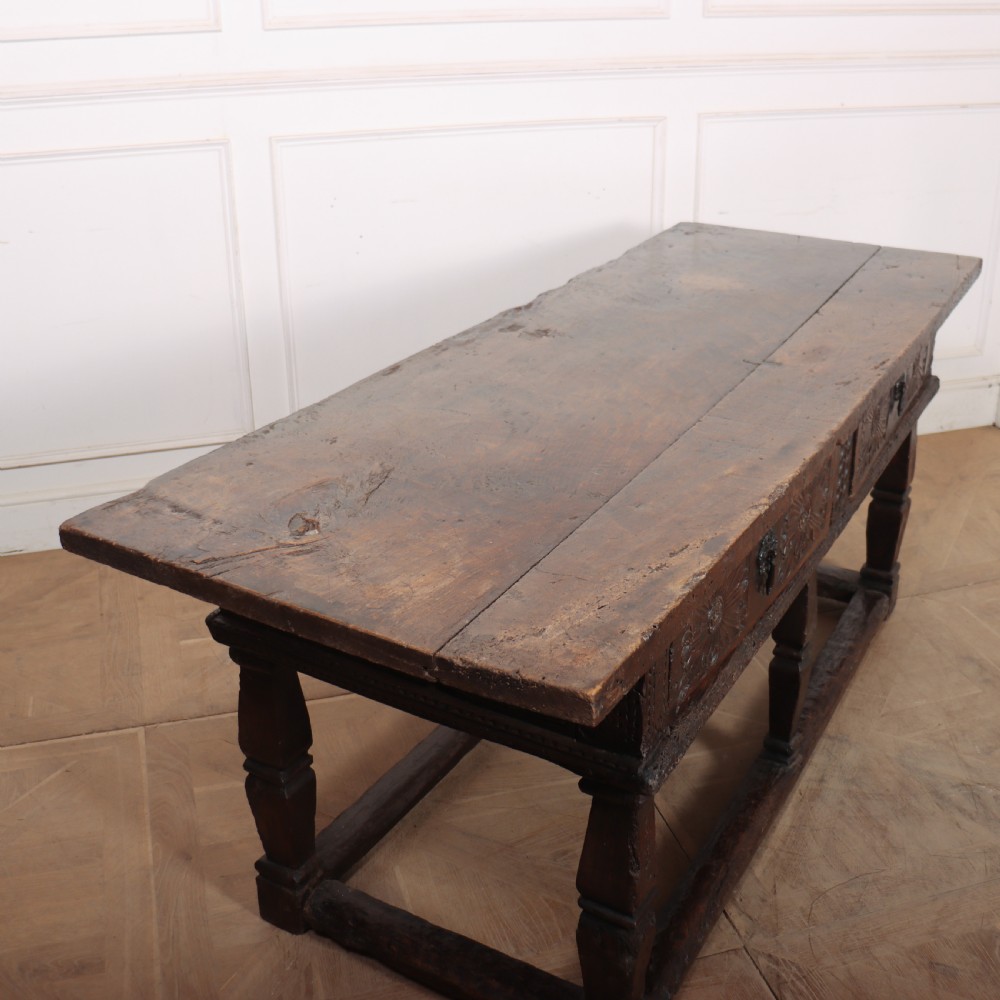 A 17th-century Spanish dark oak console table featuring carved drawer fronts with rosette motifs, turned legs, iron handles, and a box stretcher base. View XIII