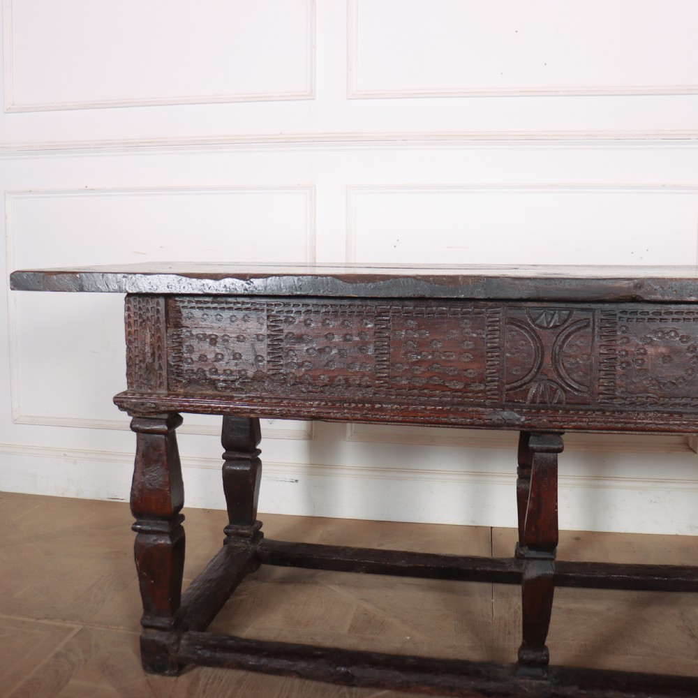 A 17th-century Spanish dark oak console table featuring carved drawer fronts with rosette motifs, turned legs, iron handles, and a box stretcher base. View XVI