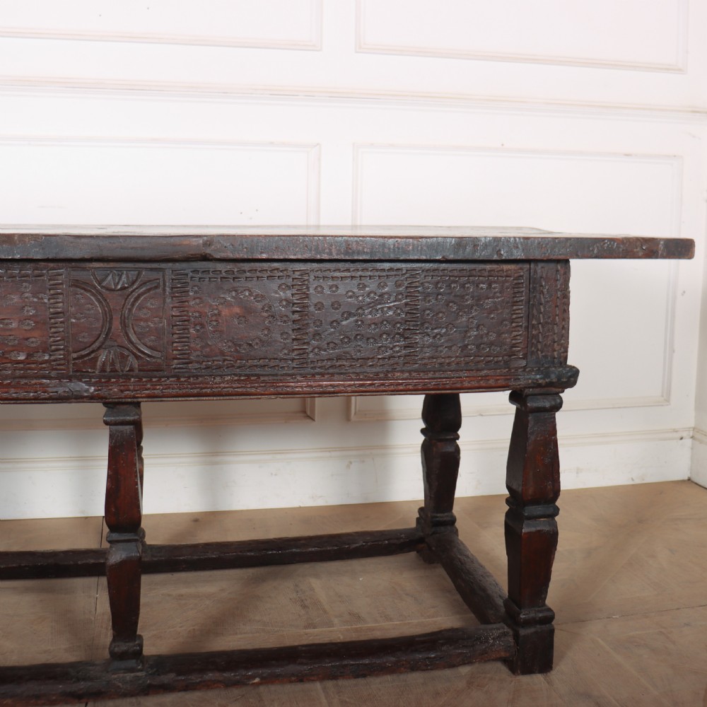 A 17th-century Spanish dark oak console table featuring carved drawer fronts with rosette motifs, turned legs, iron handles, and a box stretcher base. View XVII