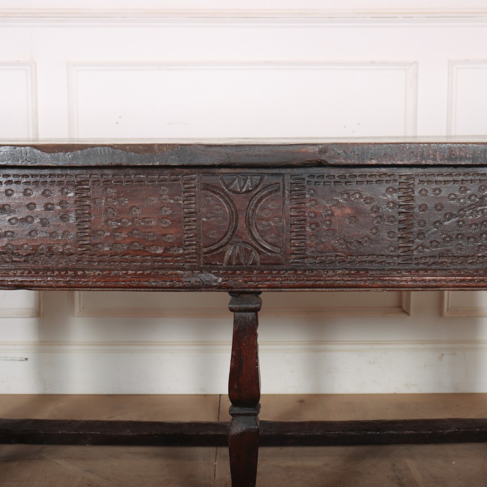 A 17th-century Spanish dark oak console table featuring carved drawer fronts with rosette motifs, turned legs, iron handles, and a box stretcher base. View XVIII
