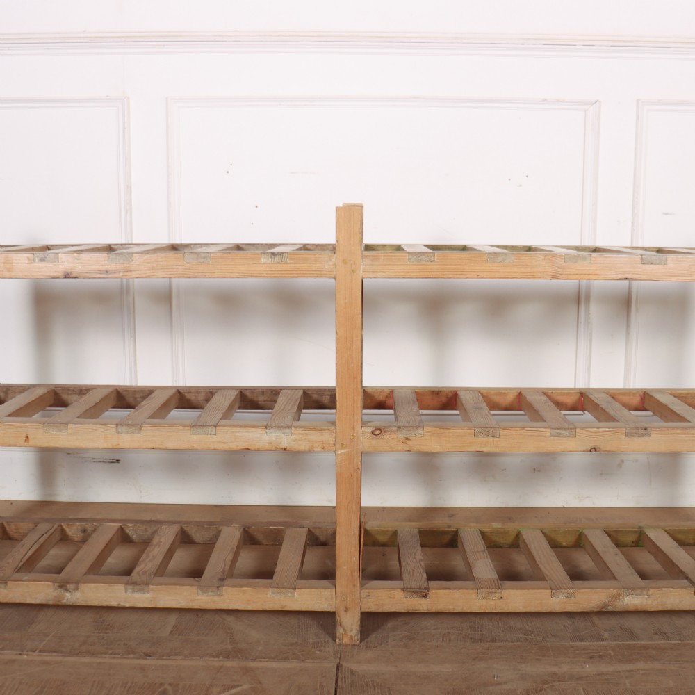 A three-tier slatted pine shoe rack with vertical support posts and a natural unvarnished wood finish. View III