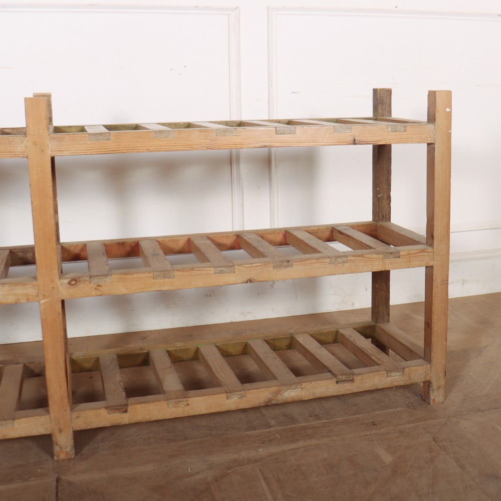 A three-tier slatted pine shoe rack with vertical support posts and a natural unvarnished wood finish. View IV