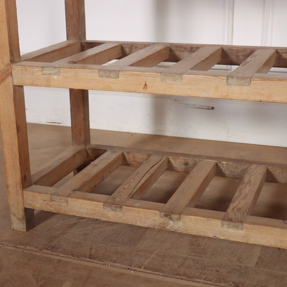 A three-tier slatted pine shoe rack with vertical support posts and a natural unvarnished wood finish. View V