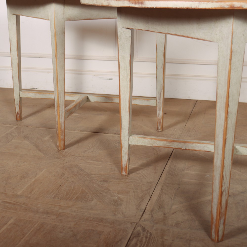 A pair of antique Swedish semi-circular console tables featuring a distressed pale grey painted finish, simple aprons, and straight tapered legs with stretchers. View II